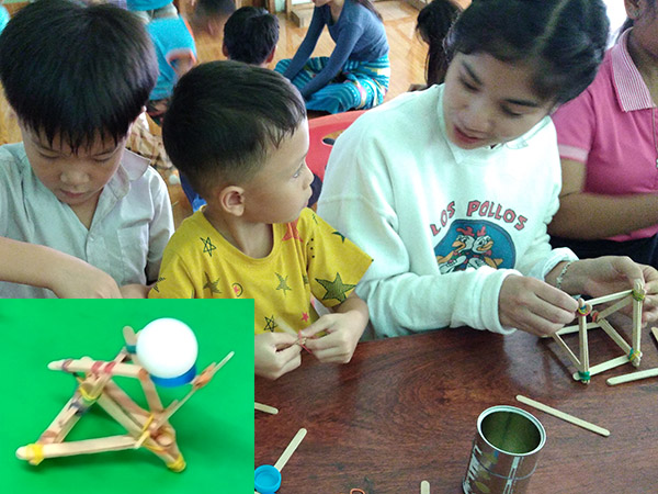 A boy and girl building something with small wooden sticks