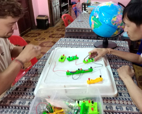 Two people making a simple electrical circuit
