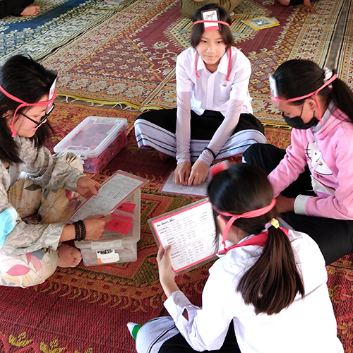A group plays What Am I, using yes-or-no questions to guess what animal is on their forehead.