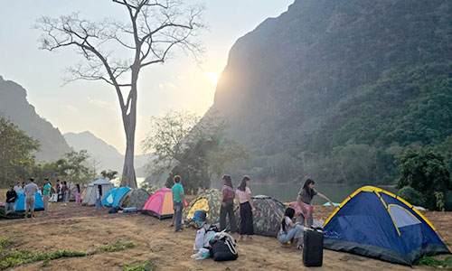 Tents pitched by river in Nong Khiaw, Laos, and children