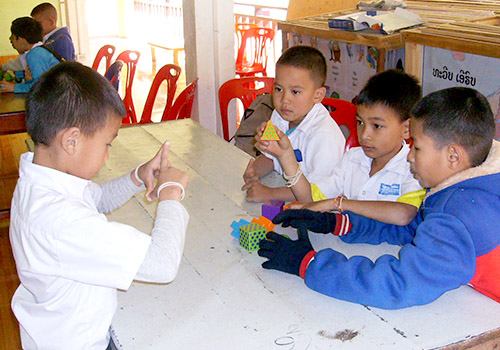 A student tells others, in sign language, how to arrange the pieces for the game Mental Blox.