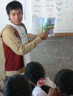 Khamla Panyasouk, a young Lao man, displays an alphabet book to a primary school class in Laos