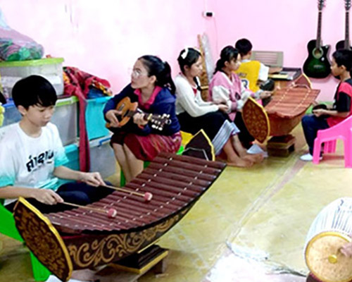 The music room at Big Sister Mouse school in Luang Prabang, Laos, with teachers and students playing the instruments