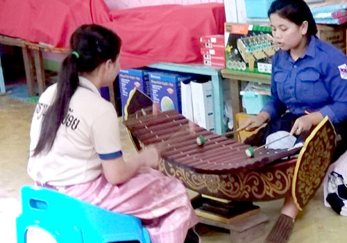 Two young Lao women play a wooden lanaat - a Lao xylophone