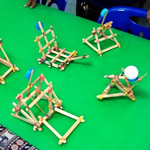 Several styles of toy catapults made of popsicle sticks and rubber bands