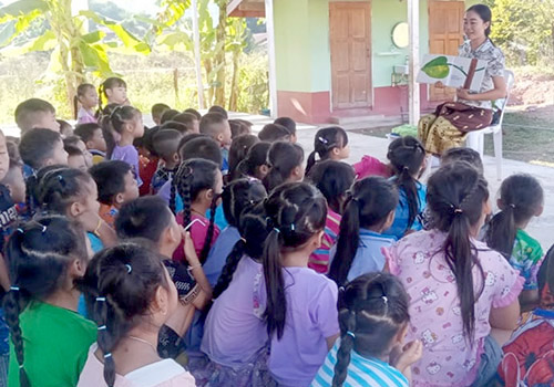 Teacher at Little Elephant preschool in Huai Xai, Laos, telling a story to a group of small boys and girls