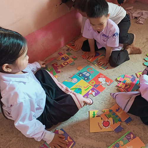 Lao children put together an easy jigsaw puzzle about the English alphabet