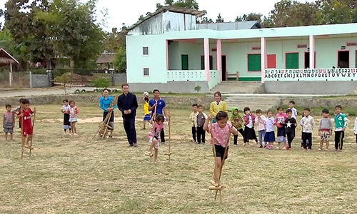 Two children participating in a stilt race at Little Rabbit School in Muang Hun, Udom Xai Province, Laos