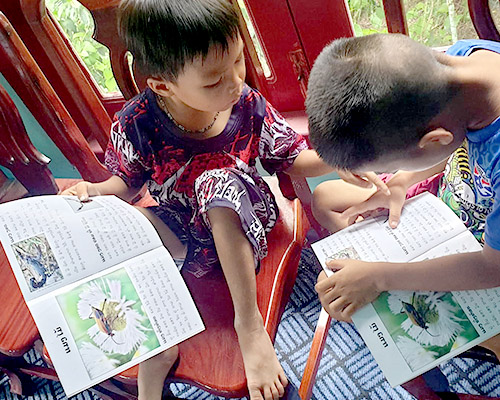 One boy helps another read a book
