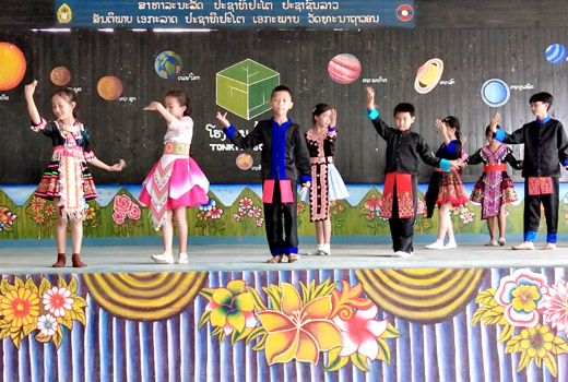 Boys and girls at Ton Kit school in Hua Na village, Laos, perform a dance, dressed in traditional costume