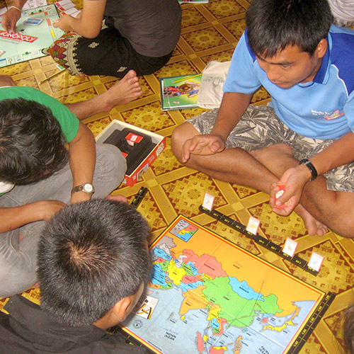Young adults sitting on the floor, playing a board game with a map in front of them