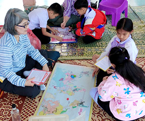 A visitor plays a geography game with students at Little Rabbit School in Laos.