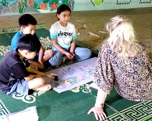 Lao children and a foreign visitor play Hop Home, a game where students get practice understanding English