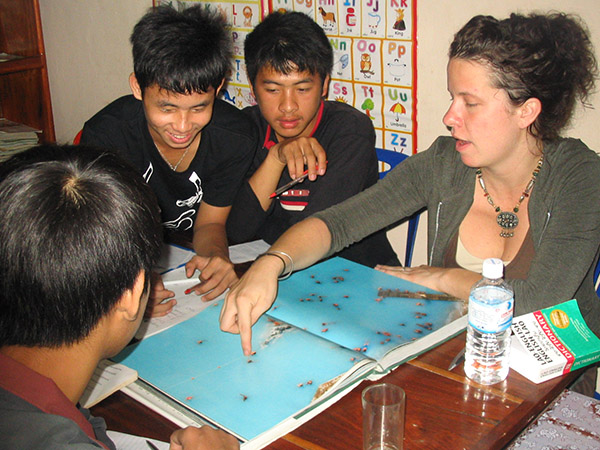 A visitor to Laos looks at an atlas with three young Laotians